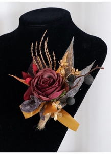 Nahaufnahme der handgefertigten weinroten Rosen-Ansteckblume mit goldenen Blättern