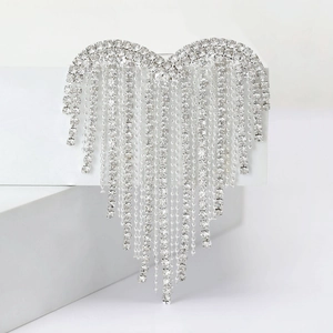 Detail of silver heart brooch with sparkling rhinestone tassels on white geometry