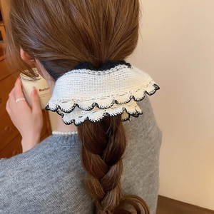 Detail view of a black and white knitted lace scrunchie styled on a low ponytail hair