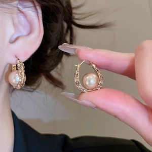 Detail of French style gold hoop earring with pavé rhinestones and a large center pearl