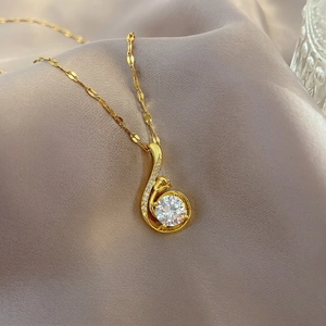 Gros plan sur collier en titane doré avec breloque rose et pendentif cristal sur soie