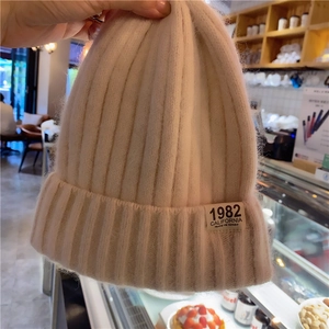 Close-up of beige knitted beanie featuring the 1982 California woven label detail