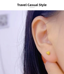 Macro detail of a 18K gold plated heart stud earring worn on the earlobe