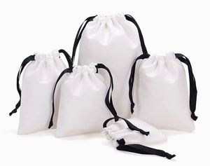 Detailed view of various sizes of white cotton drawstring gift bags with black ribbons