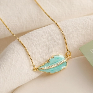 Close-up of golden leaf pendant with turquoise enamel and small zircon details