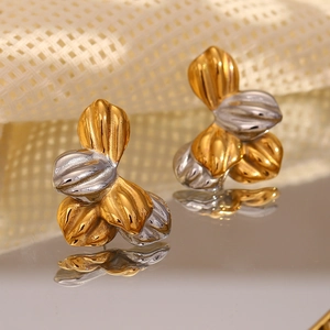 Macro view of two-tone flower stud earrings with three-petal design on a mirror surface
