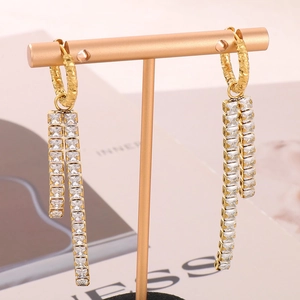 Detail of long gold tassel earrings with white square zirconia stones and hammered texture