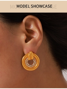 Close-up of gold round earrings with micro-paved cubic zirconia worn on a model ear