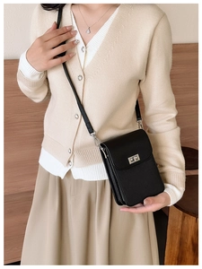 Detail view of mini black crossbody bag featuring a silver twist lock and pebble leather