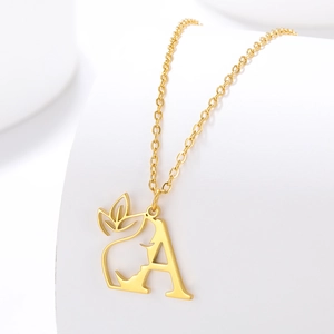 Detail of gold necklace featuring letter A and female profile silhouette pendant