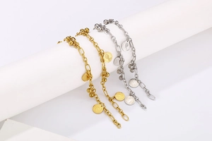 Dettaglio macro di bracciali con pendente a moneta in oro e argento su supporto bianco