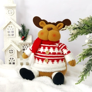 Christmas plush reindeer doll in red sweater and scarf sitting on snow background