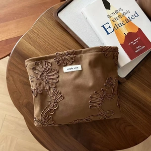 Macro view of suede cosmetic bag with floral embroidery and simple wish label
