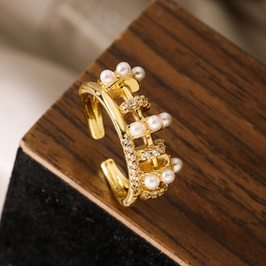 Detailed view of gold plated abacus ring with pearls and zircons on a wooden stand