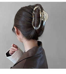 Detailed view of a large amber-patterned hair claw clip styling a low bun hairstyle