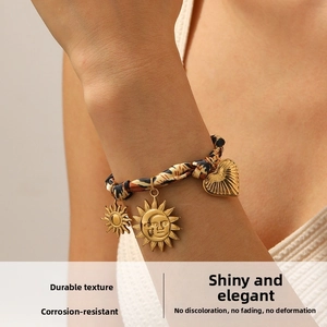 Detail of leopard print ribbon bracelet with gold sun and heart charms worn on wrist