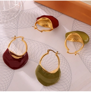 Detail of red and olive green wavy enamel earrings with golden lever back closures