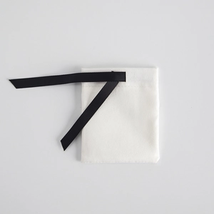 Detailed view of a white jewelry pouch with a textured black ribbon drawstring closure