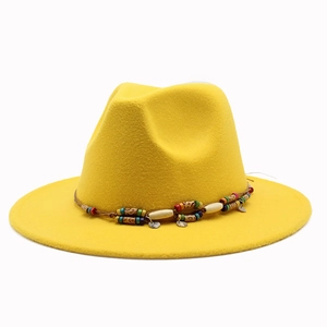 Détail du chapeau fedora jaune en laine avec bande perlée ethnique et pendentifs bohèmes
