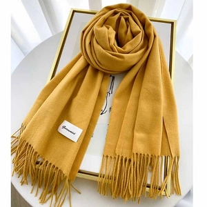Detail view of the yellow cashmere scarf featuring a soft knit texture and fringe trim