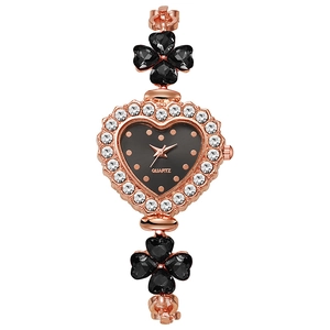 Detail of rose gold heart-shaped watch with black dial and clover crystal accents