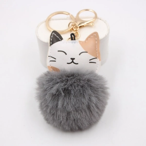 Detail showing the gray faux fur pompom and golden lobster clasp of the cat keychain