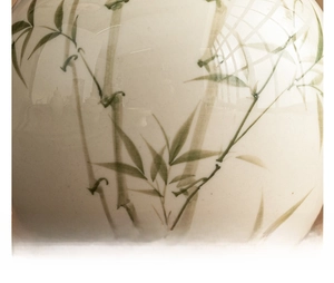 Close-up of polished ceramic tea canister featuring a translucent glaze and ink bamboo motif