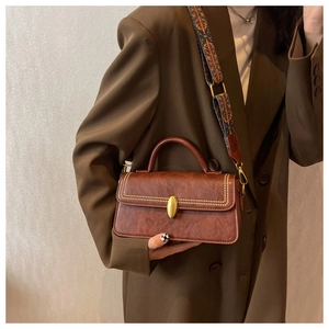 Close-up of vintage brown leather bag with golden studs and ethnic embroidery strap