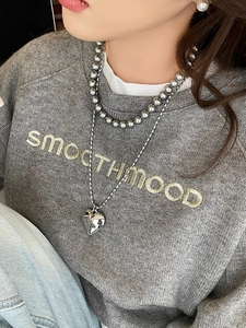 Layered silver heart pendant necklace with beaded chain and pearl earring detail