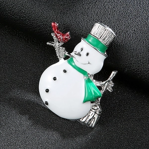 Close-up of a festive enamel snowman brooch with a red scarf on black leather background