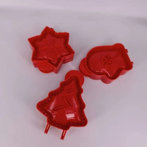 Macro shot of 3 red plastic Christmas baking molds in star, mitten, and tree shapes