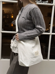 Close-up of white canvas tote bag featuring blue polka dots and woven side strap detail