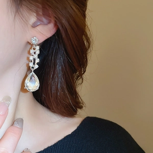 Primo piano di un modello che indossa orecchini a goccia d'argento con cristalli lucenti