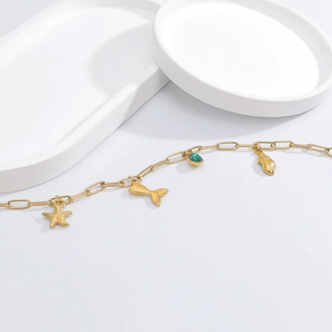 Detail of 18K gold-plated bracelet with starfish, seashell, and green gemstone charms