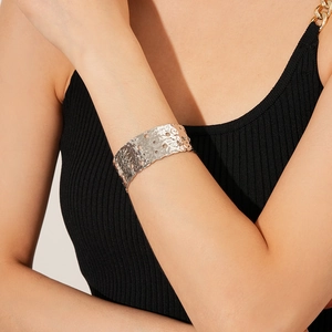 Detailed macro view of wide silver-plated hammer textured cuff bracelet with hollow holes