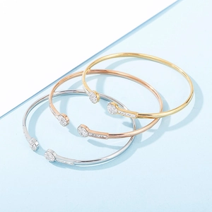 Gros plan détaillé de trois bracelets joncs étincelants en finitions or, argent et or rose