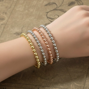 Close-up of stacked gold silver and rose gold elastic beaded bracelets on vintage paper