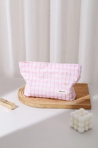 Détail de la trousse de toilette rose à carreaux avec broderie nœud et étiquette de marque