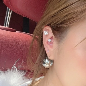Close-up of sparkling cubic zirconia magnetic ear studs and silver hoop earring on ear