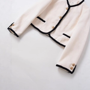 Veste classique en tweed crème avec bordure noire contrastée et boutons dorés
