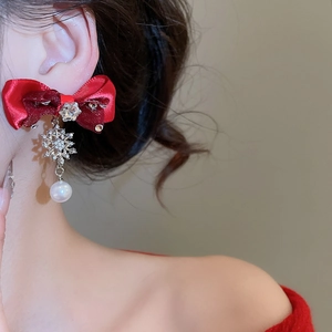 Close-up of red ribbon bow earrings with diamond snowflake and pearl on model
