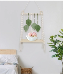 Detail of bohemian macrame wall shelf with woven leaves and light wood shelf board