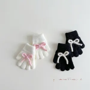 Detailed view of plush knit gloves featuring soft fabric and cute bow tie accents