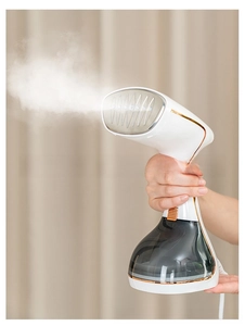 Powerful handheld garment steamer spraying white steam on beige fabric backdrop