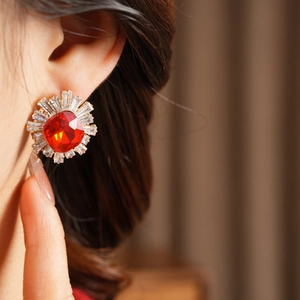Close-up of vintage sunburst stud earrings with ruby red center stone and white crystals