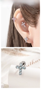 Macro shot of silver micro-paved zircon cross cartilage stud earrings in pink, blue, and clear