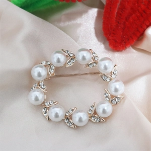 Detailed close-up of a gold pearl wreath brooch with small sparkling crystals on satin
