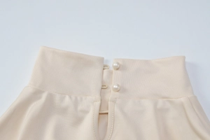 Détail de l'encolure de la robe en tricot avec boutons de perles sur tissu beige
