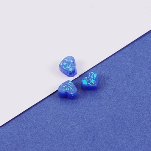 Macro shot of three blue heart-shaped resin opal beads with holographic sequins and side holes