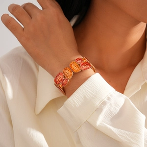 Close-up of orange geometric enamel bangle with hammered gold edges on model's wrist
